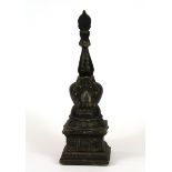 A Tibetan cast bronze model stupa with a small figure of a seated Buddha embedded in clay, H. 20cm.