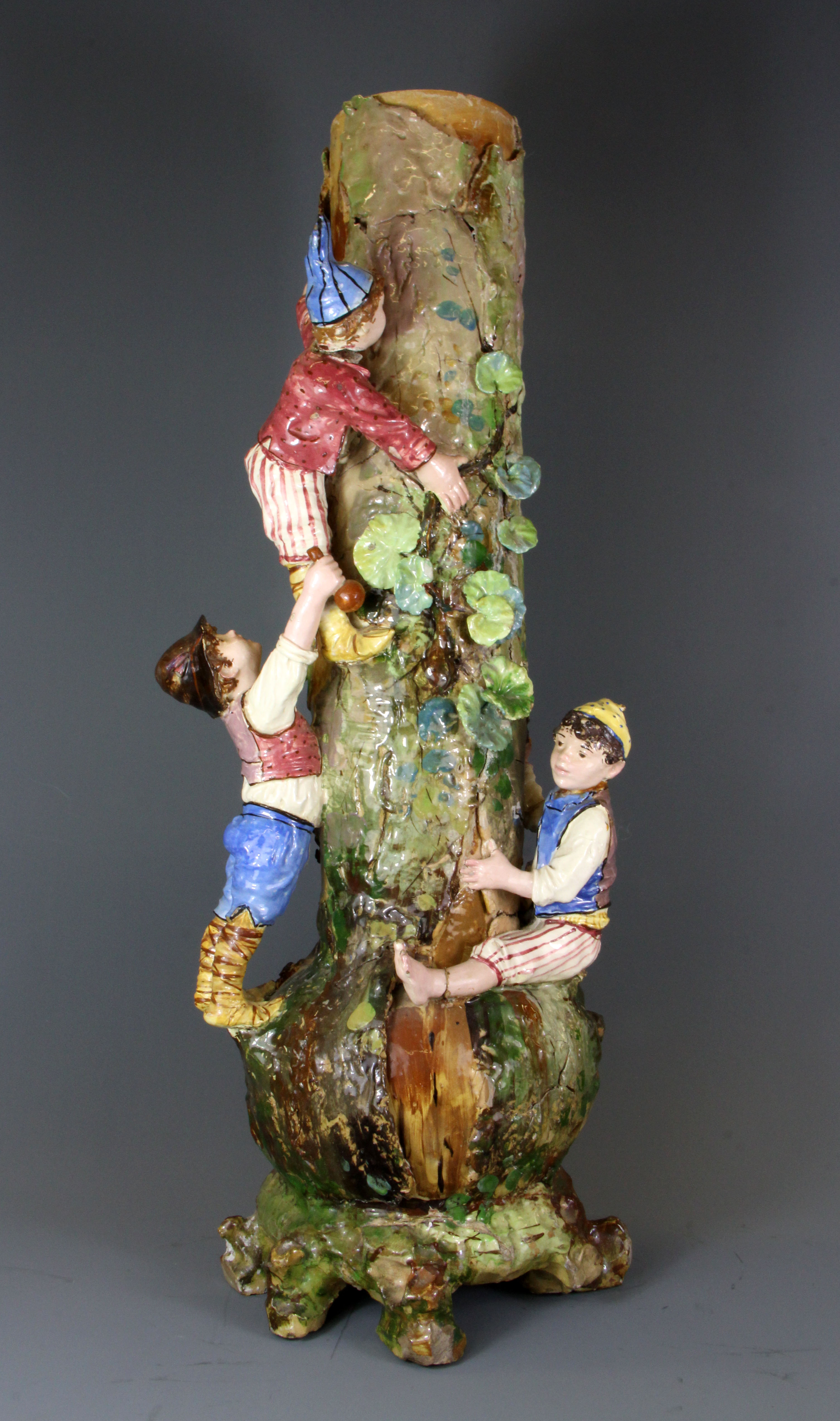 A large early 20th Century hand made pottery vase of children climbing a tree, H. 60cm.