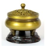 A small Chinese gilt bronze censer, the lid decorated with bats, on a carved wooden stand, H. 9cm.