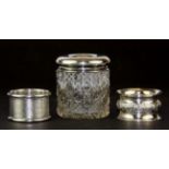 Two silver napkin rings and a silver topped hair tidy.