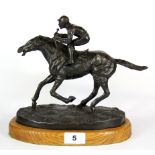 A bronze sculpture of a jockey raised on a wooden base, after Mene, H. 23cm.