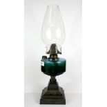 A Victorian oil lamp with cast iron base and green glass well, H. 50cm.