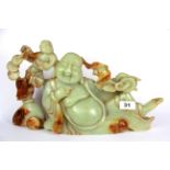 A large Chinese carved celadon green and russet jade/ hardstone figure of the reclining happy Buddha