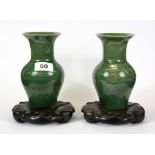 A pair of Chinese green glazed porcelain vases on carved wooden lotus petal stands, total H. 18cm.