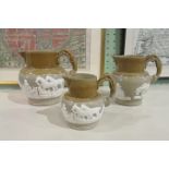 A graduated set of three half-glazed stoneware harvest jugs,
