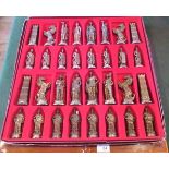 A set of cast white and gilt metal chess pieces, variously fashioned as Vikings and other soldiers,