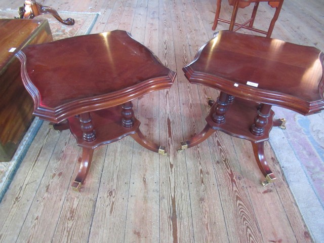 A pair of George IV-style cartouche topped mahogany side tables on splayed and castor supports.