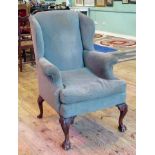 A George II-style hipped wingback fire side chair, raised on bold carved cabriole supports.