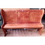 A pitch pine pew, having three panel back on shaped end supports united by a pegged seat stretcher.