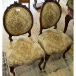 A pair of late Victorian walnut parlour chairs, each having ribbon tied florally carved rail,