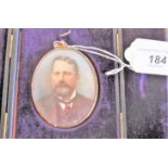 A gilt metal cased oval portrait miniature of an Edwardian gentleman in formal attire,