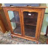 An Edwardian oak bookcase, the rectangular top with moulded edge over a pair of glazed doors,