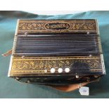 An early/mid-20th century Hohner 14 key accordion in a black lacquered gilt decorated case.