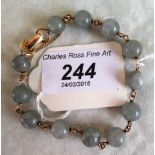 A mottled grey jade bead bracelet, yellow metal interspersed links and clasp,