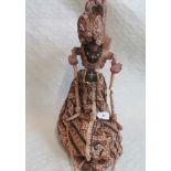 A Balinese carved and painted stick puppet in decorative ethnic dress.