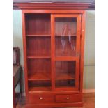 A contemporary cherry wood veneered bookcase, the moulded cornice over sliding doors,