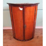 A George III oak and mahogany crossbanded barrel fronted corner cabinet,