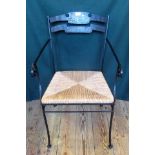 A wrought iron open armchair, having a two rail shaped leather back, woven seat, scrolled arms,