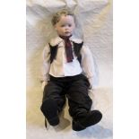 A large contemporary bisque head doll, fashioned as a young boy with blond wig,