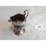 A George III pedestal helmet form cream jug with double scroll handle and spreading foot,