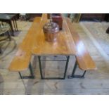 A varnished pine folding trestle-type table, together with a pair of conforming benches.