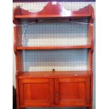 An Edwardian wall mounting set of open shelves with a two cupboard door base.