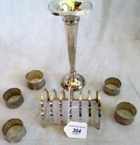 A silver trumpet shape vase with loaded base, a silver toast rack and five serviette rings,