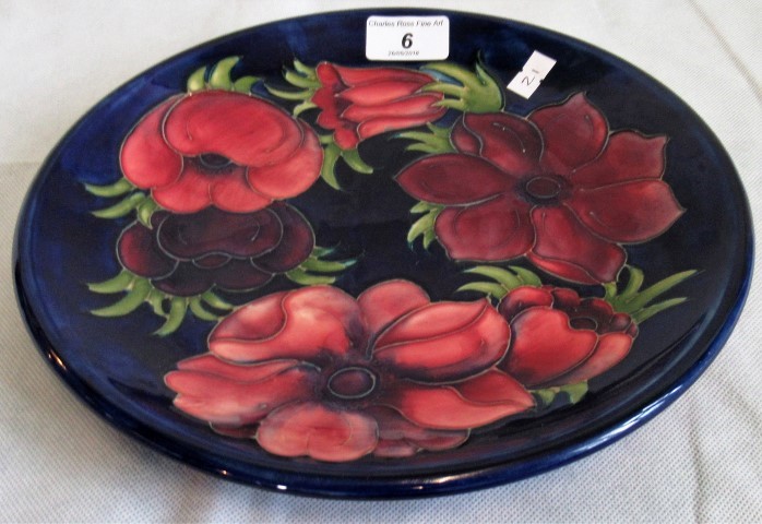 A Moorcroft tube lined floral plate on a blue ground.