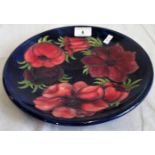 A Moorcroft tube lined floral plate on a blue ground.