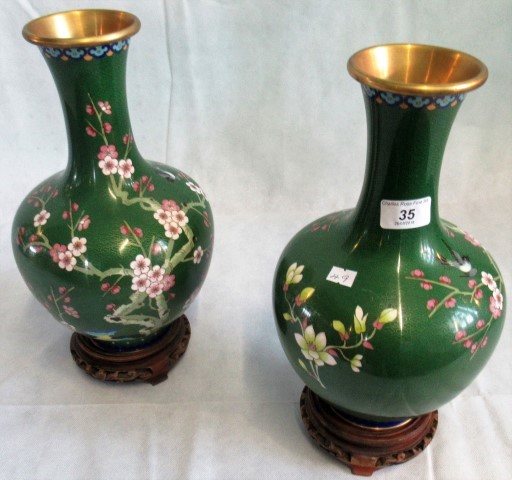 A pair of 20th century jade green ground Oriental cloisonne vase on carved wooden stands.