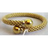 A precious yellow metal flexible fancy link bangle with polished spherical terminals,