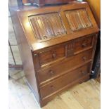 A reproduction oak bureau, having a linen fold panel fall,