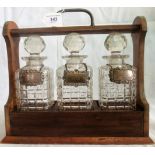 A nickel mounted oak three bottle Edwardian tantalus,