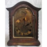 An early 20th century oak cased eight day mantle clock with arched top and spiral pilasters,