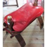 A camel seat with red hide upholstered pad.