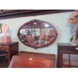 An oval mahogany framed wall mirror.