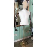 A half-mannequin, with articulated wooden arms on a brass stand.