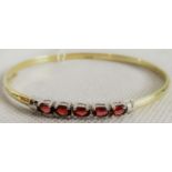 A five stone gem set bangle, the horizontally set oval cut stone to plain polished bangle.