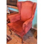 A 20th century wing armchair in terracotta draylon.