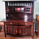 An Arts & Crafts oak dresser with galleried super structure over central mirrored panel,