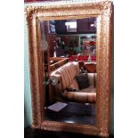 A profusely carved gilt framed wall mirror with central bevelled plate.