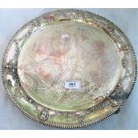 A silver circular tray, heavily decorated in relief and engraving with inscription to centre,