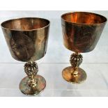 A pair of silver goblets, each bowl bearing a heraldic motif with an otter and fish engraved above,