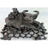 A 20th century carved hardwood figure of a recumbent water buffalo with an Oriental gentleman on