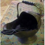 A brass helmet shaped coal scuttle, complete with tongs and coal.