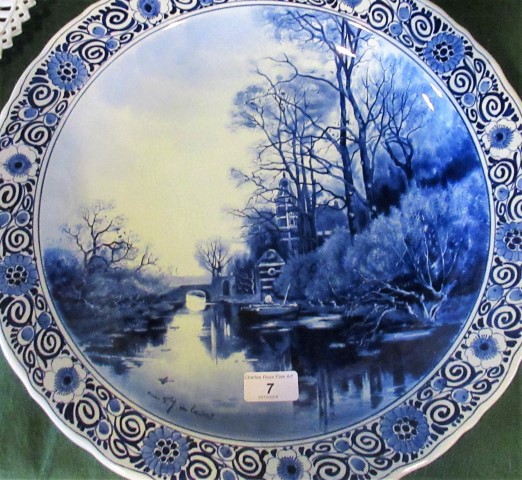 A late 19th/early 20th century blue and white Delft charger, depicting a river and woodland scene,