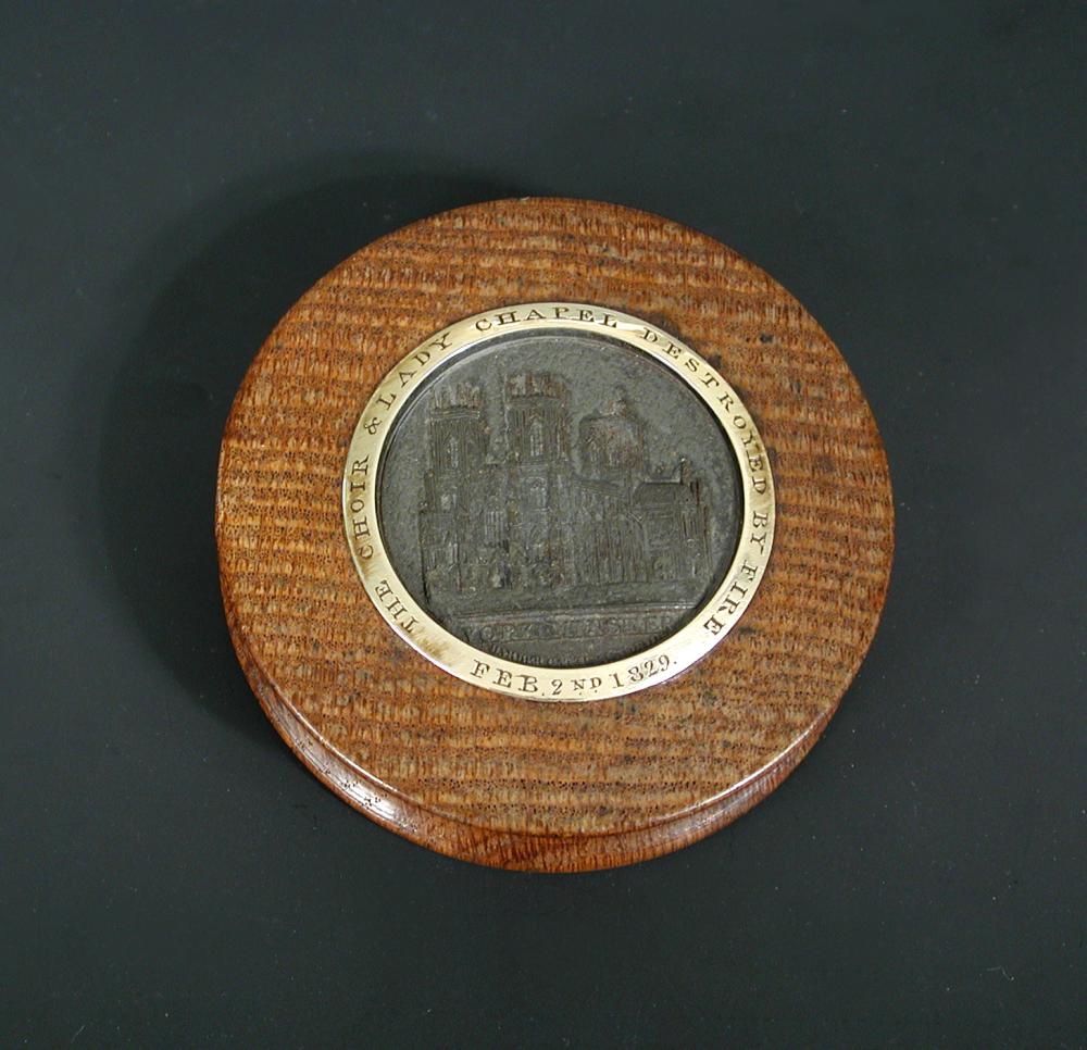A York Minster 1829 circular oak snuff box with central bronze medallion within gold metal band