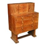 An Arts & Crafts Cotswold School oak bureau, with cupboard and drawer superstructure above a fold-