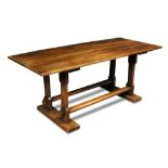 An Arts & Crafts walnut refectory table, the rectangular top supported to either end by a pair of