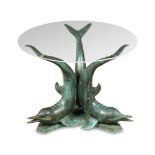 A glass topped coffee table with bronze dolphin base, the circular top supported on three cast